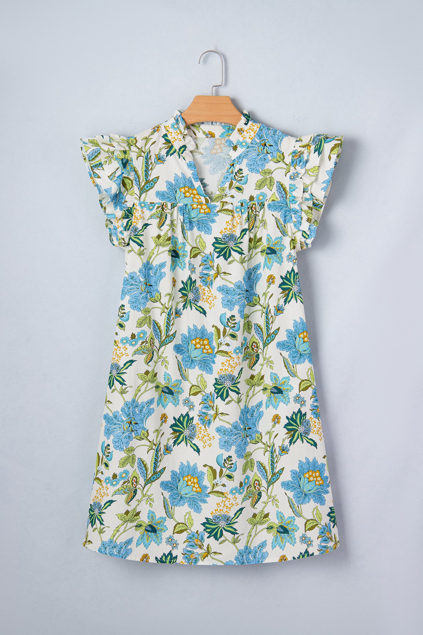 Floral dress with blue flowers on a hanger against a gray background