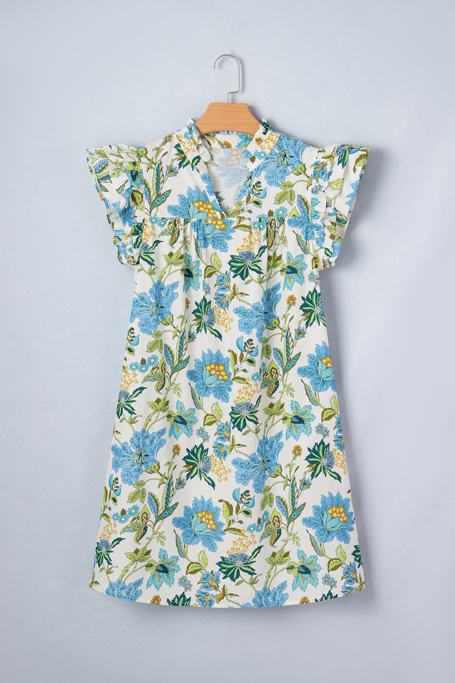 Floral dress with blue flowers on a hanger against a gray background