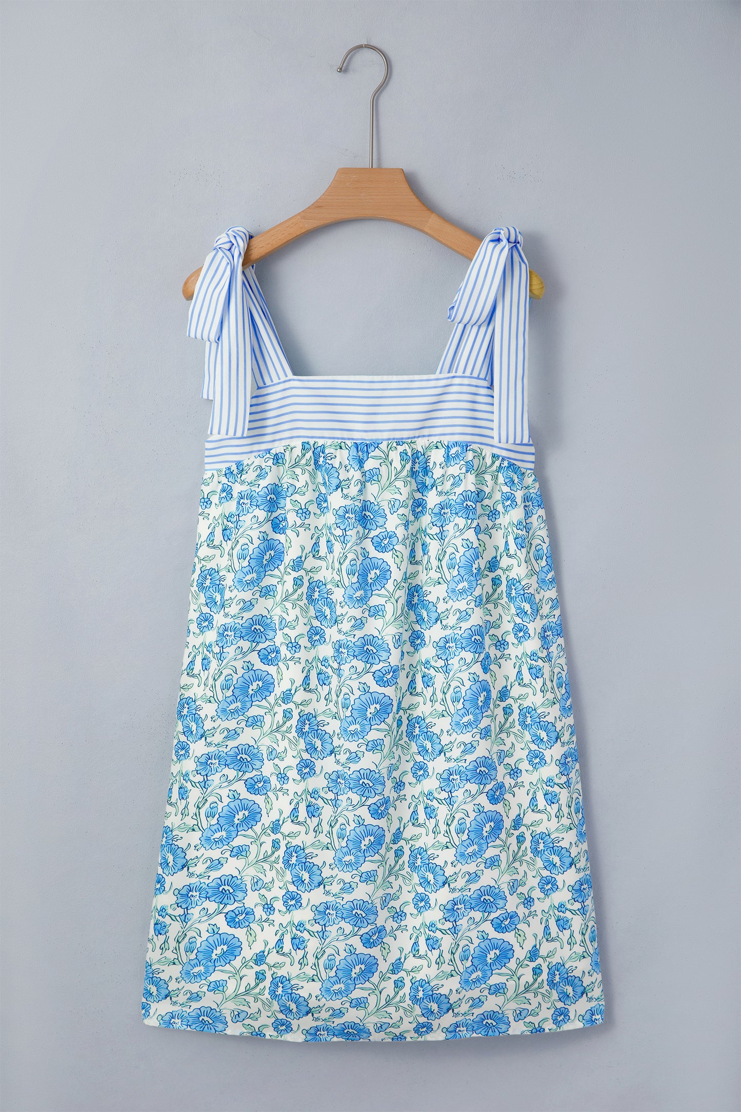 Blue floral dress on a hanger against a gray background