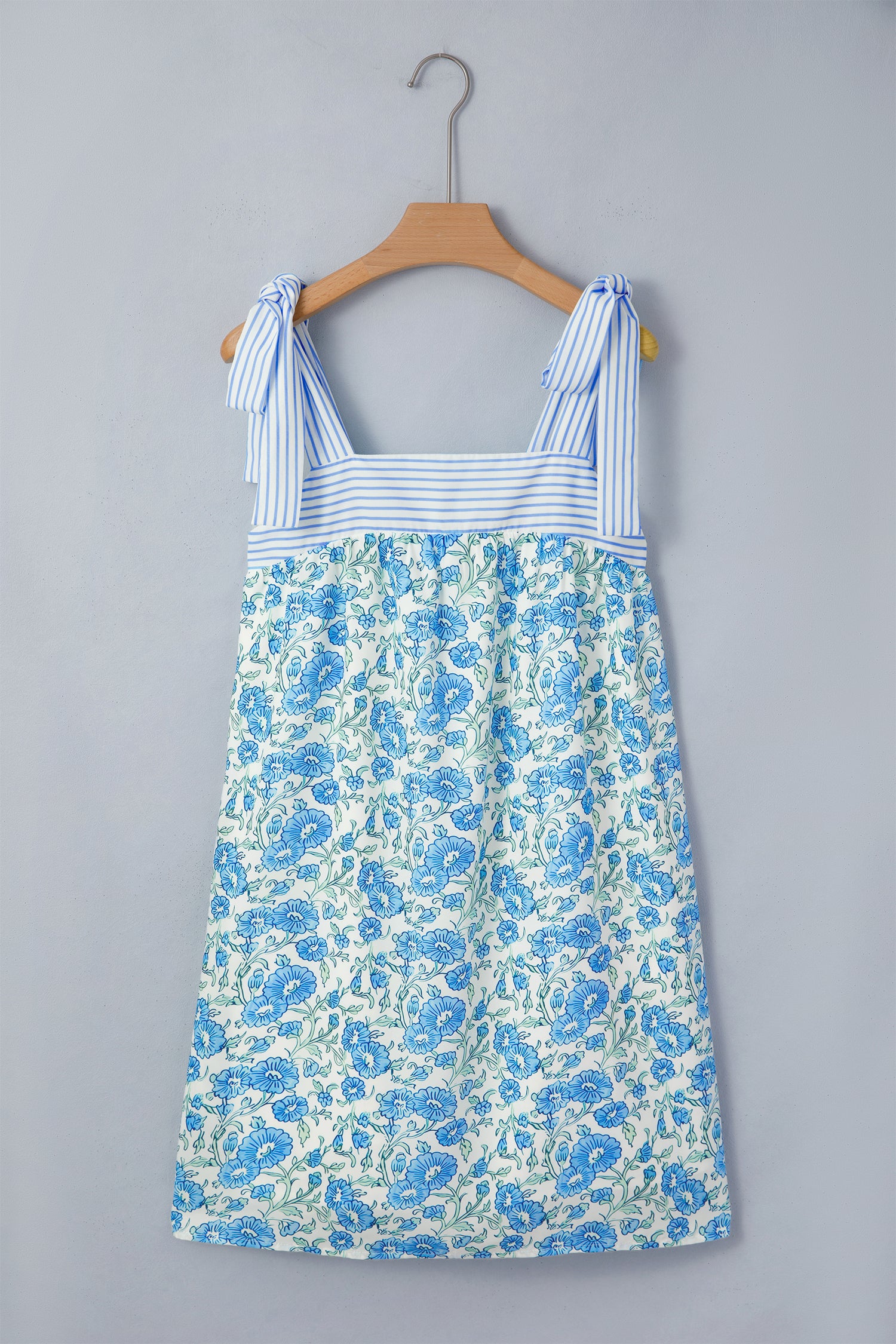 Blue floral dress on a hanger against a gray background